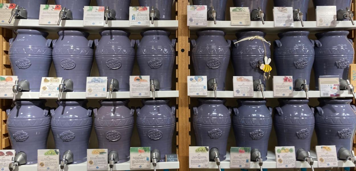 Gerhard Scholler steht zwischen den Regalen im Feinkost-Laden vomFASS St. Pölten und hält eine Flasche in der Hand. Foto: kommunikationsagentur-sengstschmid