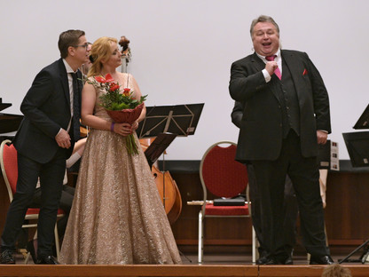 Zwei männliche und eine weibliche Sängerin auf einer Bühne.