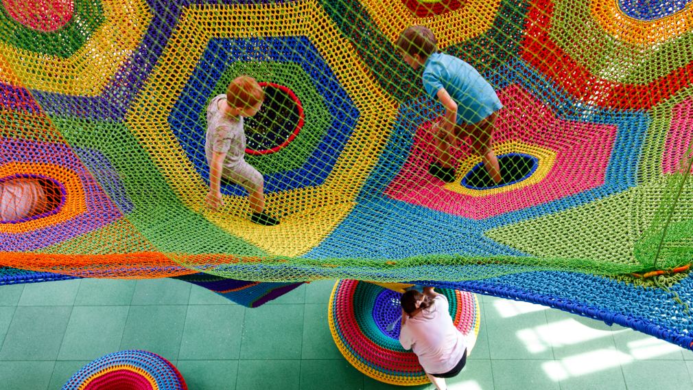 Toshis Gabe ist eine interaktive dreidimensionale textile Landschaft aus gehäkelten Sechsecken, offenen Taschen und hängenden Pendelkörpern. Sie ermöglicht die imaginative und lebendige Erkundung von Farben und Formen und ist stimulierender Raum zum Spielen.  (Foto: Max Kropitz)