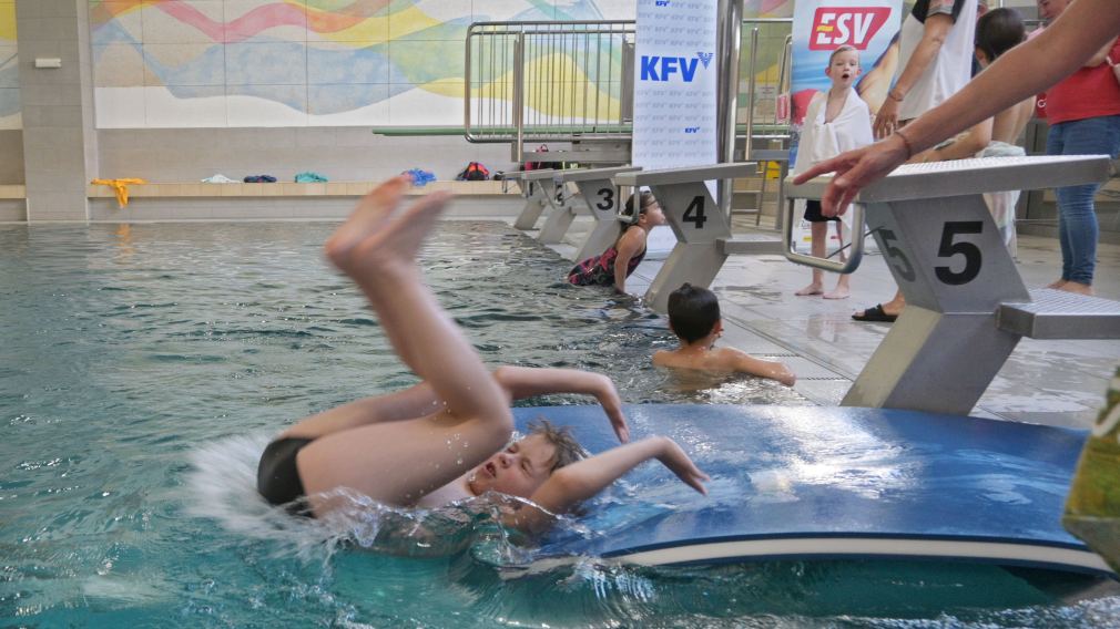 Ein Mädchen, das an einem Selbstrettungsschwimmtraining teilnimmt, springt in ein Schwimmbecken.