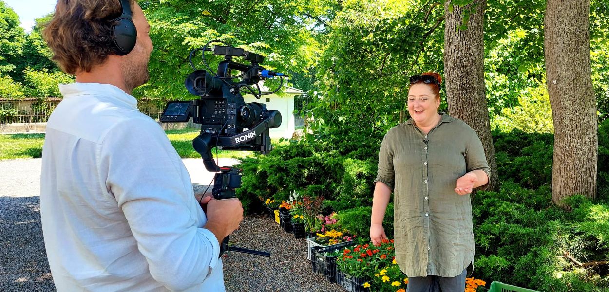 Veronika Polly plauscht im Garten der Musikschule, Bernhard Brunnthaler filmt.