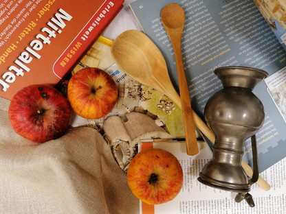Äpfel, Kochlöffel und ein Buch auf einem gedeckten Tisch. (Foto: Eva Birk)