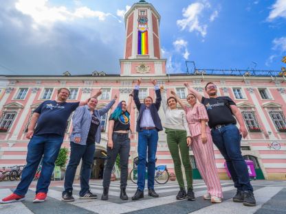 ST. Pride Vereinsmitglieder Erwin Rossmann, Elke Bandion, Tris Endl, Bürgermeister Matthias Stadler, Ilse Knell und Mariella Schlossnagl vom Büro für Diversität und ST. Pride Vereinsobmensch Oskar Beneder vor dem Rathaus mit Progress Pride Fahne am Rathausturm. (Foto: Arman Kalteis)