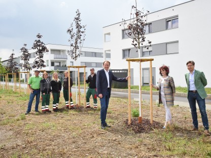 Acht Personen bei einer neu gepflanzten Baumallee beim Wohnbau der gemeinnützigen Bau-, Wohn- und Siedlungsgenossenschaft Alpenland in der Gerdinitschstraße. (Foto: Josef Vorlaufer)