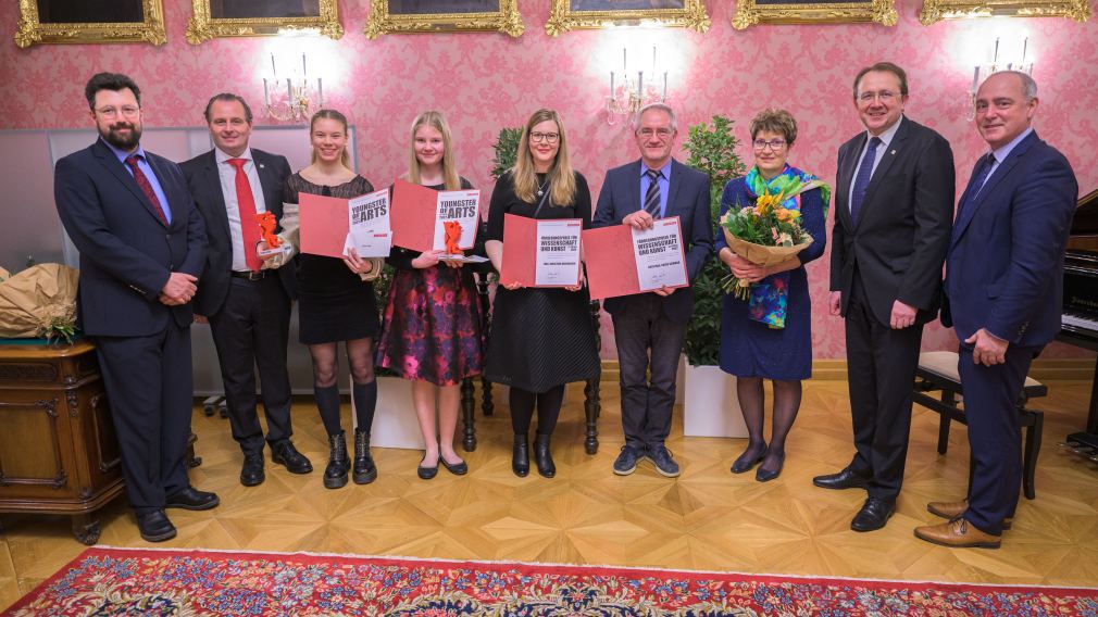 Neun Personen posieren für ein Gruppenfoto im Bürgermeisterzimmer bei der Preisverleihung. (Foto: Arman Kalteis)