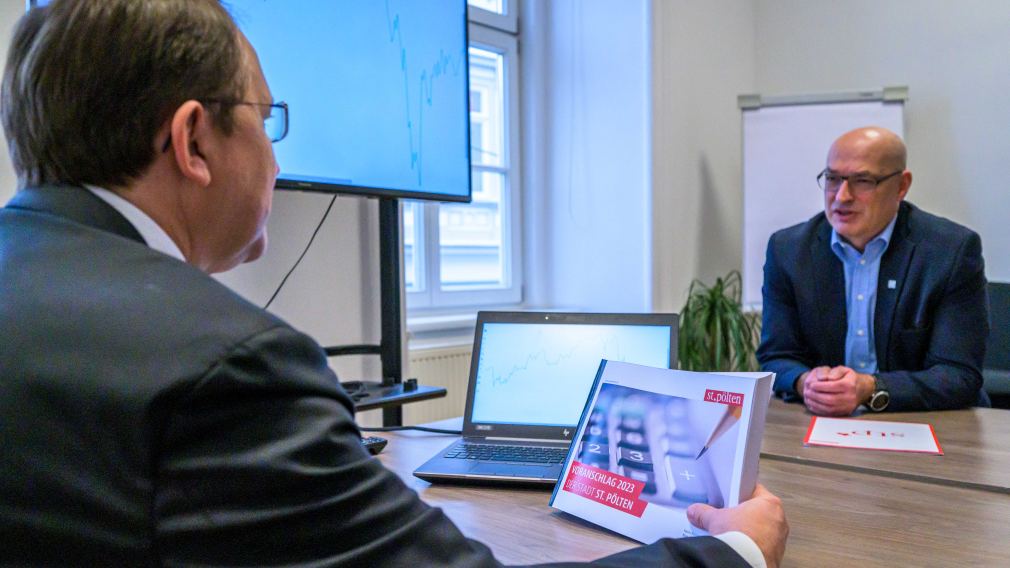 Zwei Personen mit einem Buch und Bildschirm an einem Tisch. (Foto: Kalteis)