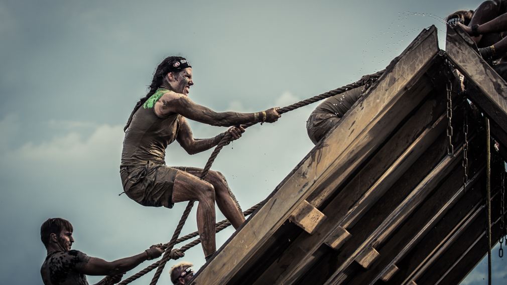 Eine Frau beim überqueren von Hindernissen. Spartan Race