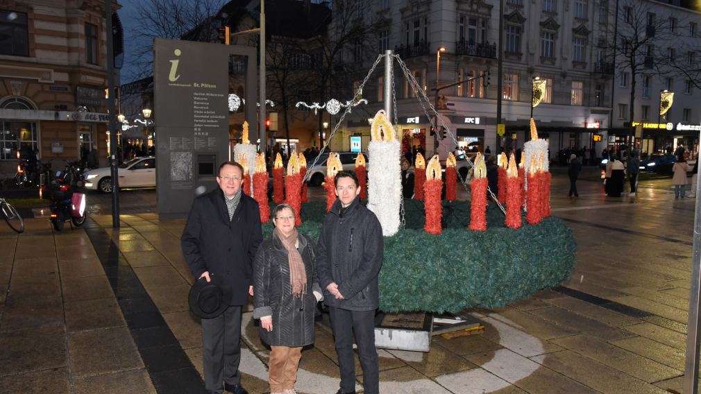 Bürgermeister Matthias Stadler, Superintendentialkuratorin Gisela Malekpour und Superintendent Michael Simmer der Evangelischen Kirche Niederösterreich vor dem mit 24 Kerzen gebundenen Adventkranz am Bahnhofplatz. (Foto: Josef Vorlaufer)