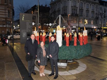 Bürgermeister Matthias Stadler, Superintendentialkuratorin Gisela Malekpour und Superintendent Michael Simmer der Evangelischen Kirche Niederösterreich vor dem mit 24 Kerzen gebundenen Adventkranz am Bahnhofplatz. (Foto: Josef Vorlaufer)