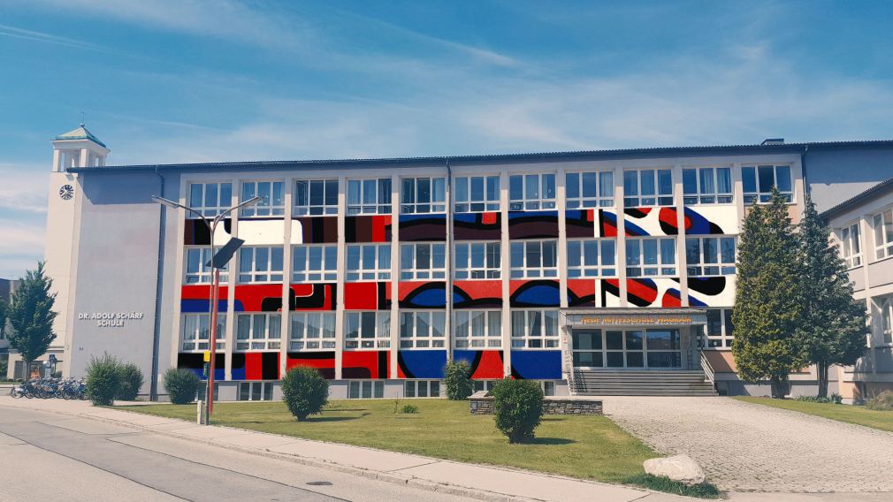Eine Fotobearbeitung der Fassade der Dr. Adolf Schärf Schule mit Bannern als Hommage an Klaus Sandler. (Illustration: Phillip Walser)