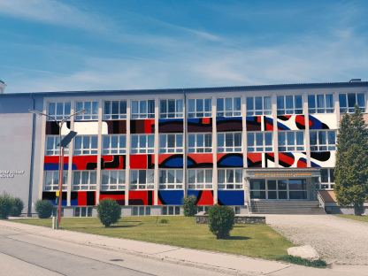 Eine Fotobearbeitung der Fassade der Dr. Adolf Schärf Schule mit Bannern als Hommage an Klaus Sandler. (Illustration: Phillip Walser)