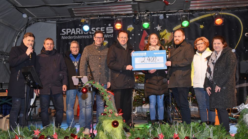 Der Scheck wurde im Beisein einiger Sponsor:innen und des Bürgermeisters am Christkindlmarkt der Sozialhilfe übergeben. (Foto: Josef Vorlaufer)