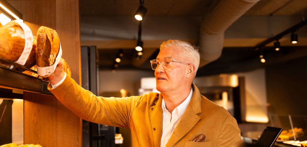 Wolfgang Hager greift ins Brotregal seiner Bäckerei Hager. Foto: Bäckerei Hager GmbH+KG