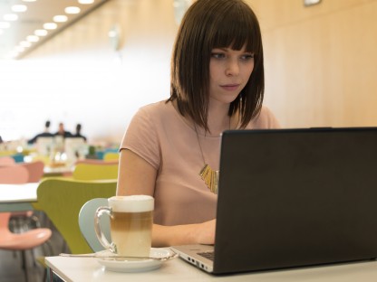 Eine junge Frau in der Mensa der Fachhochschule St. Pölten, sitzend mit einem Laptop. (Foto: Martin Lifka)