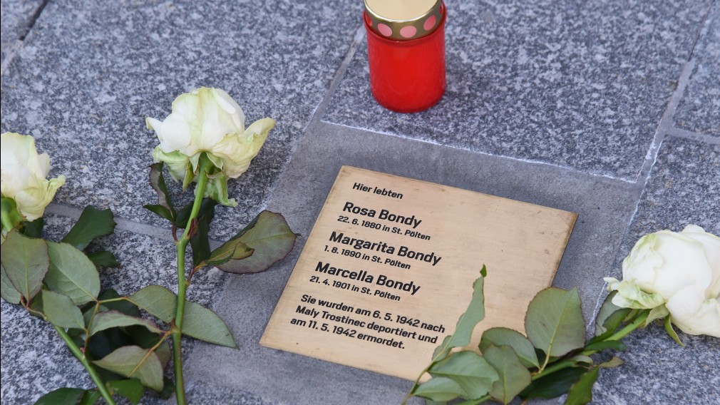 Gedenktafel mit Namen eingraviert , Kerzen und Rosen. (Foto: Josef Vorlaufer).
