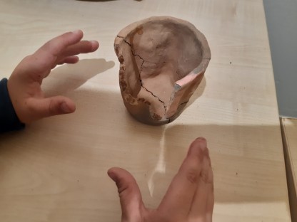 Kinderhände und ein Keramikgefäß mit Rissen. (Foto: Stadtmuseum).