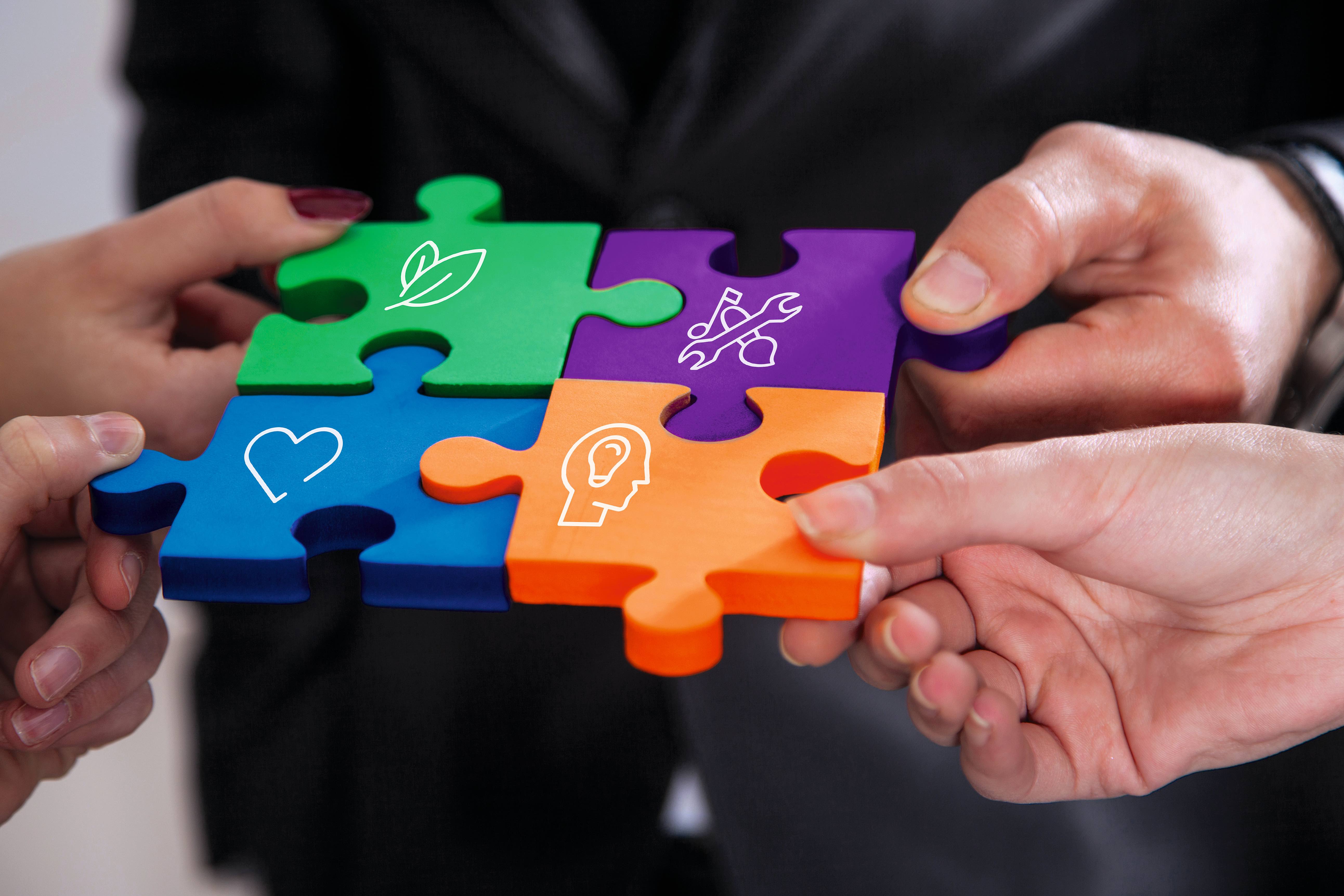 Group of business people assembling jigsaw puzzle and represent team support and help concept in office